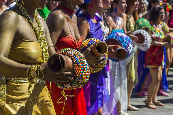 Pessoas tocando instrumentos utilizados no afoxé, ritmo musical presente no carnaval brasileiro.