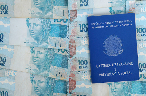 Carteira de trabalho sobre notas de R$ 100,00 representando o emprego informal.