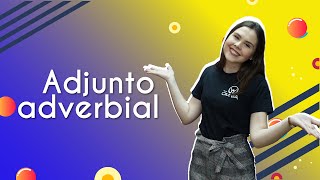 "Adjunto adverbial" escrito sobre fundo colorido ao lado da imagem da professora