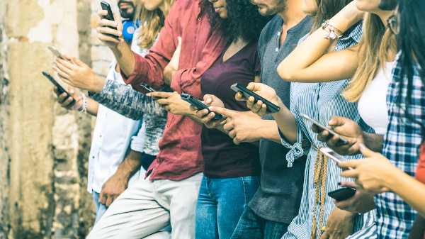 Jovens da geração z com celulares nas mãos.