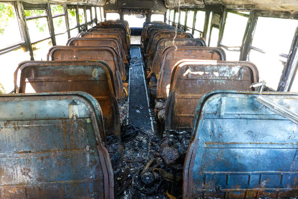 Interior de um ônibus abandonado com bancos queimados.