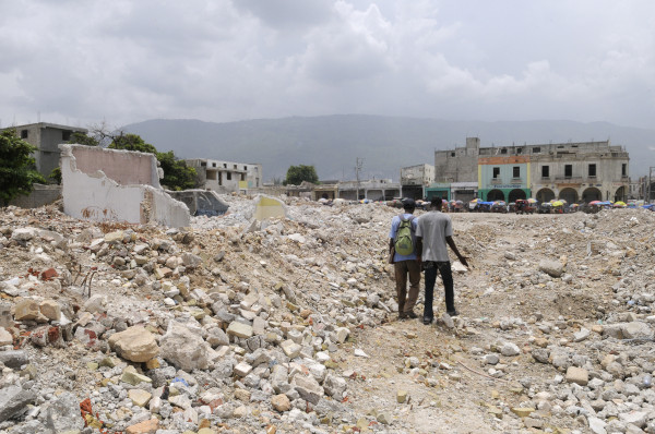 Pessoas caminham sobre os escombros de edifícios destruídos pelo terremoto que acometeu o Haiti em 2010.