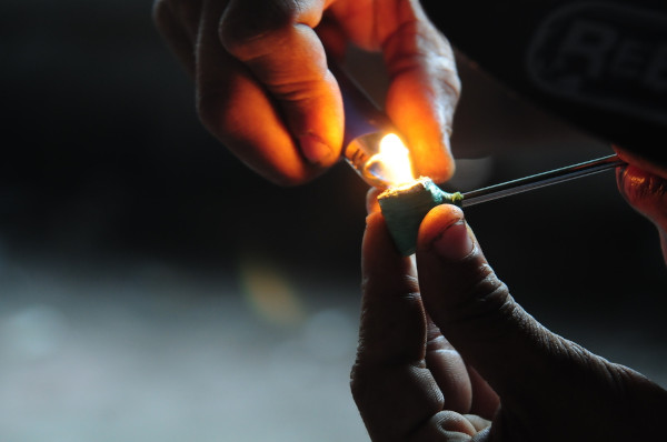Pessoa acendendo cachimbo com isqueiro.