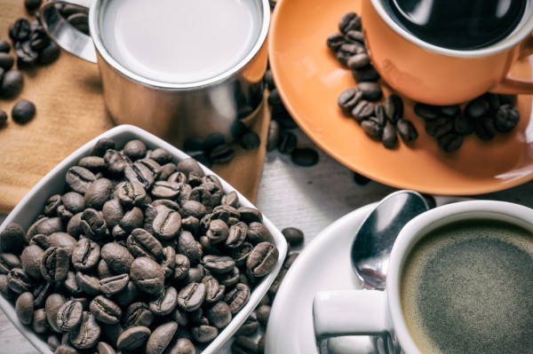 Café em grãos e xícaras com café.