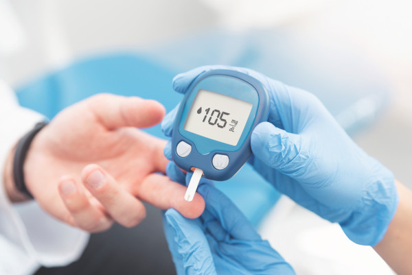 Médico verificando o nível de açúcar no sangue do paciente com glicosímetro.