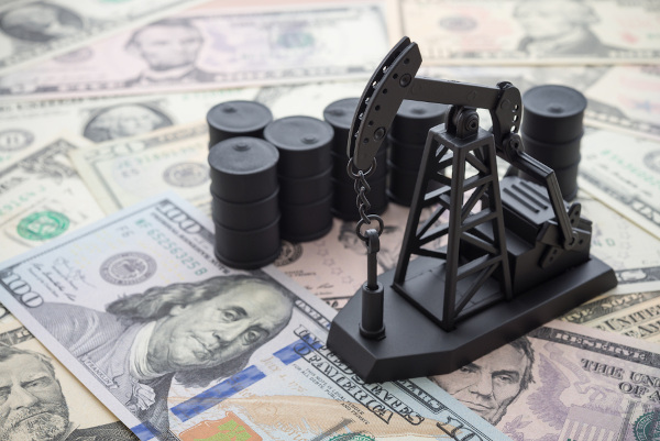 Miniatura de bomba envolvida em extração de petróleo sobre notas de dólar.