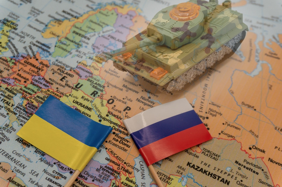 Bandeiras da Ucrânia e da Rússia, próximas a um carro-tanque de brinquedo, sobre um mapa da Europa.