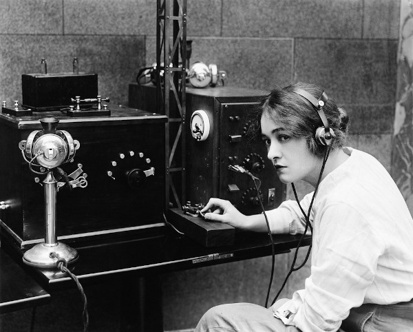 Fotografia em preto e branco de uma mulher operando uma estação de telegrafia.