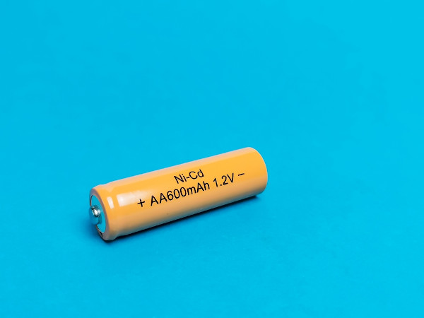 Bateria de níquel-cádmio de cor amarela sobre uma plana superfície azul.