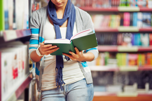 Mulher segura livro em biblioteca