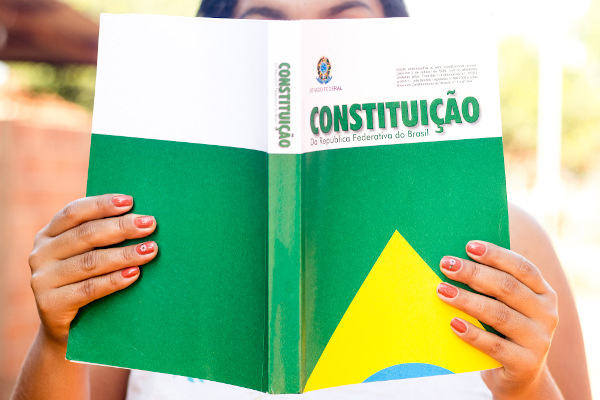 Mulher segura a Constituição do Brasil.