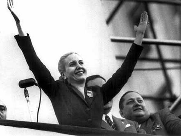 Eva Perón sorrindo de braços abertos, saudando sua audiência