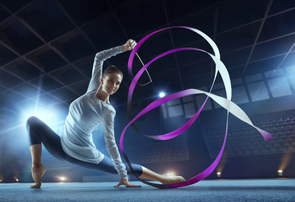 Ginasta praticando ginástica rítmica com fita.