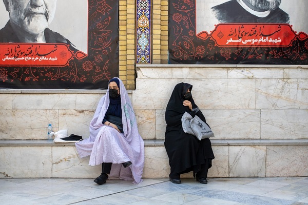 Uma mulher em um hijab está na frente de um tanque.