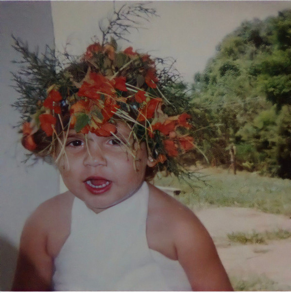 Marília Mendonça criança com coroa de flores em um jardim