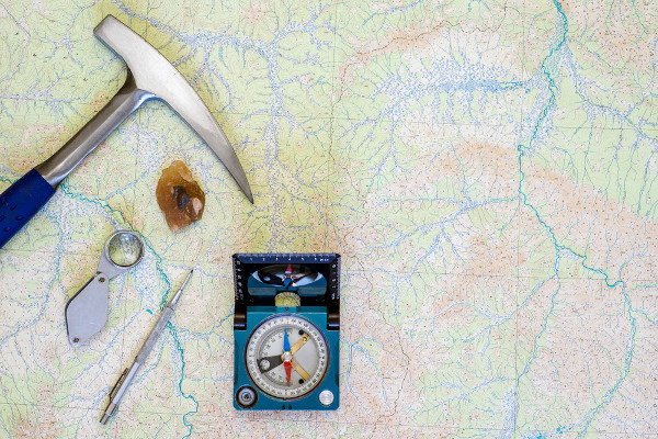 Ferramentas utilizadas pelos profissionais da área da Geologia sobre um mapa disposto em uma mesa.