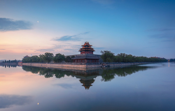 Simetria de reflexão ocorrendo em água, com imagem de prédio e paisagem sendo refletida no lago em frente. 