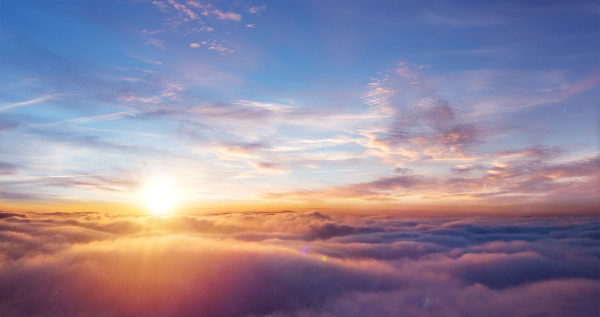 Vista de um pôr do Sol sobre as nuvens, com o céu apresentando várias cores.