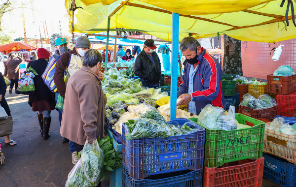 Homem vendendo frutas, verduras e legumes em uma feira, provenientes da agricultura familiar.