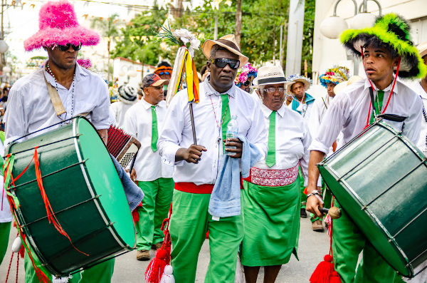 Grupo de pessoas com roupas e instrumentos coloridos em um festejo de congada.