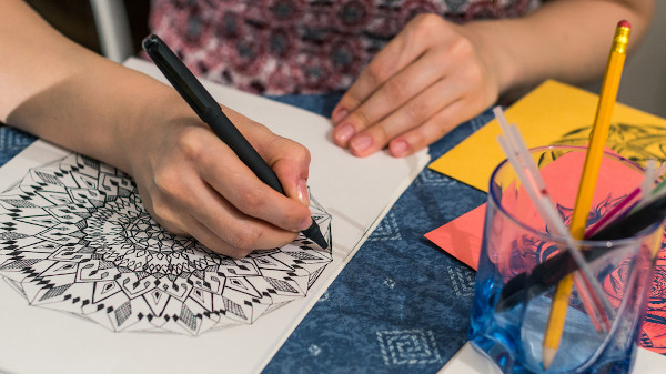 Mulher desenhando uma mandala.