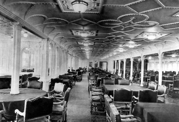 Mesas e cadeiras em uma sala de jantar do RMS Titanic.