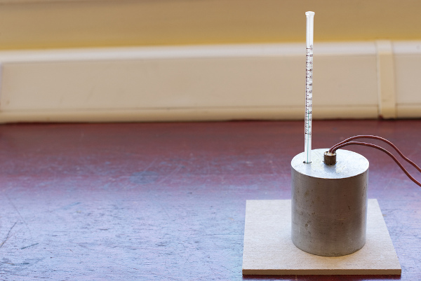 Calorímetro, usado para medição do calor específico do alumínio, sobre uma tábua de madeira.