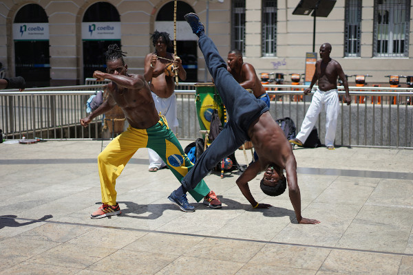 Dois homens lutando capoeira em um espaço público de Salvador, na Bahia.