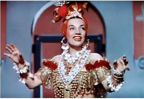 Carmen Miranda, cantora que interpretava marchinhas de Carnaval, vestida com colares e turbante durante apresentação.