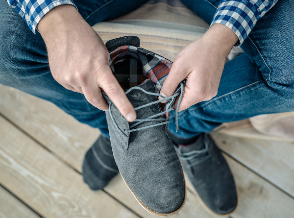 Homem inspecionando calçado antes de calçá-lo, a fim de evitar acidente com animais peçonhentos.