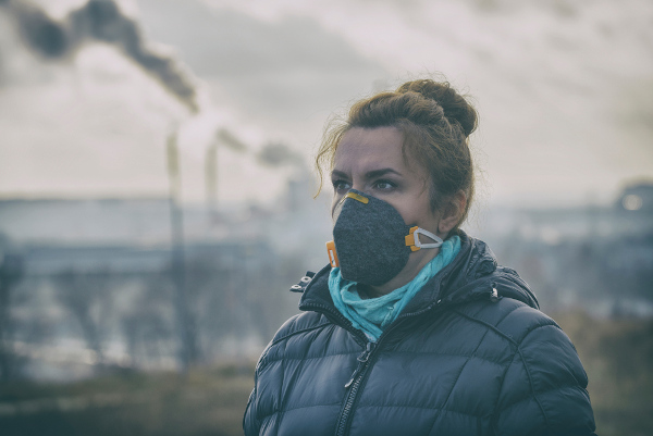 Mulher usando máscara em uma região de poluição atmosférica, um dos principais problemas ambientais do Brasil e do mundo.