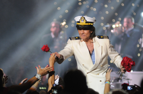 Roberto Carlos distribuindo rosas vermelhas em seu show.