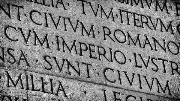 Palavras em latim inscritas em placa de concreto.