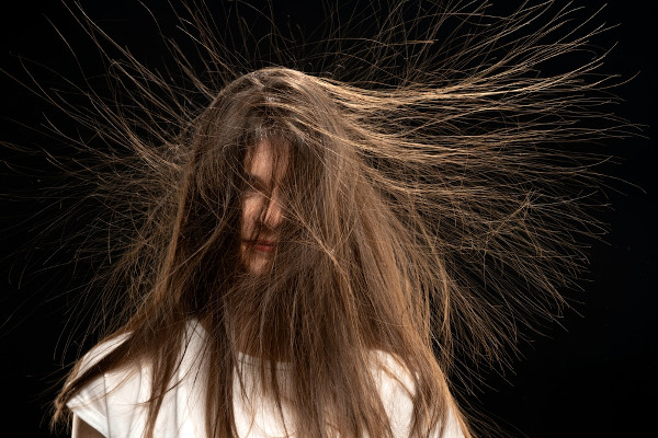 Mulher com os cabelos arrepiados como epresentação da ação da eletricidade estática.