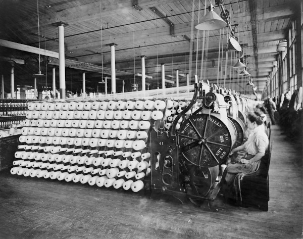 Mulheres trabalhando em máquinas têxteis em referência ao modo de produção propiciado pela Revolução Industrial.