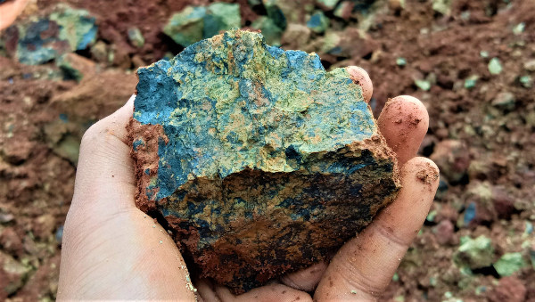 Mão humana segurando um peridotito, uma rocha que compõe o manto terrestre.