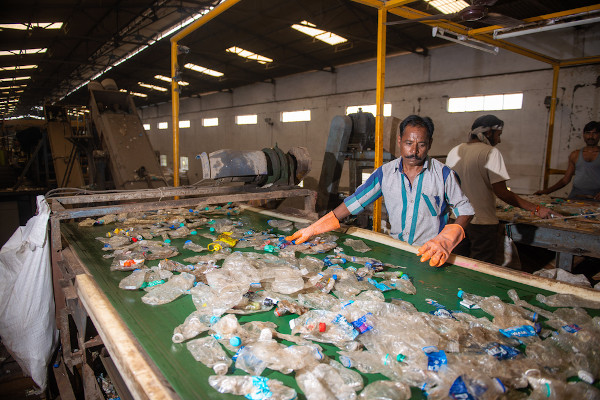 Trabalhadores fazendo a separação de garrafas de plástico PET para reciclagem.