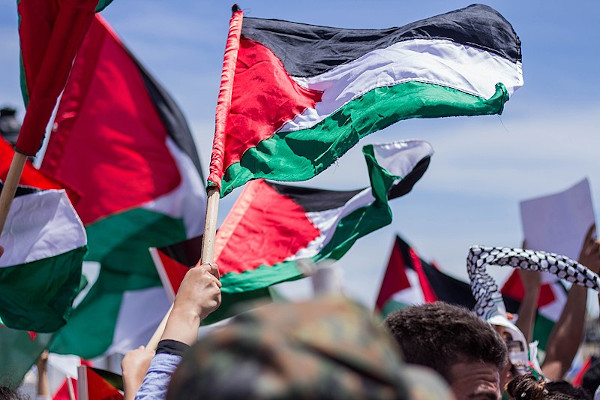 Palestinos segurando bandeiras, povo que faz parte de uma nação sem Estado.