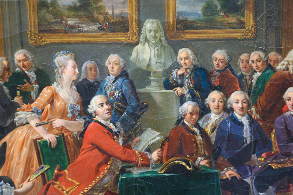 Pintura mostrando pessoas reunidas no sal&atilde;o liter&aacute;rio da Madame Geoffrin durante a leitura de uma das obras de Voltaire.
