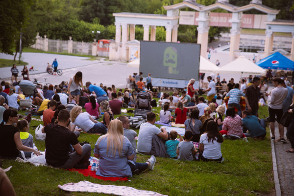 Pessoas assistindo a um filme ao ar livre, uma forma de aprender nas férias.