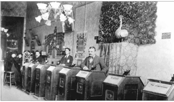 Fotografia mostrando pessoas usando cinetoscópios da empresa de Thomas Edison, invenção que antecedeu a história do cinema.