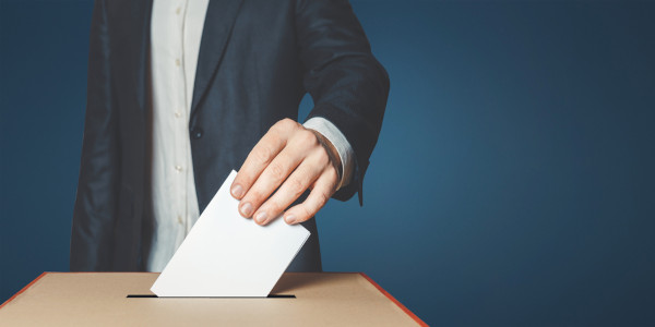 Pessoa depositando seu voto, cuja manipulação pode estar ligada ao clientelismo, em uma urna de votação.