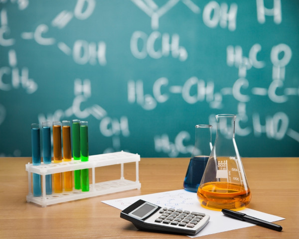 Objetos químicos sobre mesa de madeira, elementos que podem ser utilizados no cálculo da molaridade ou concentração molar.