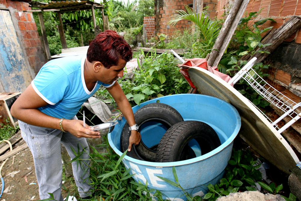 Homem próximo a pneus, que podem ser criadouros do Aedes aegypti, transmissor da dengue