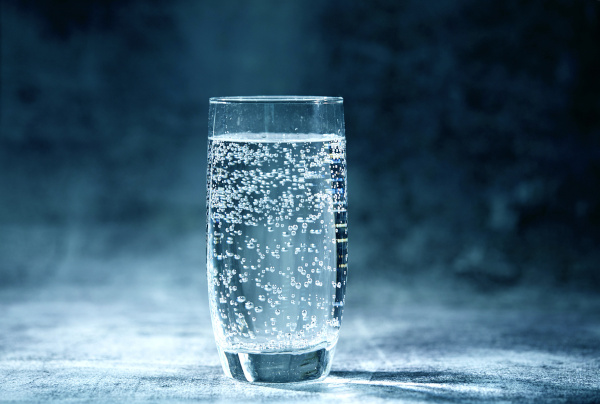 Copo com água com gás, bebida carbonatada na qual o dióxido de carbono (CO₂) está presente.