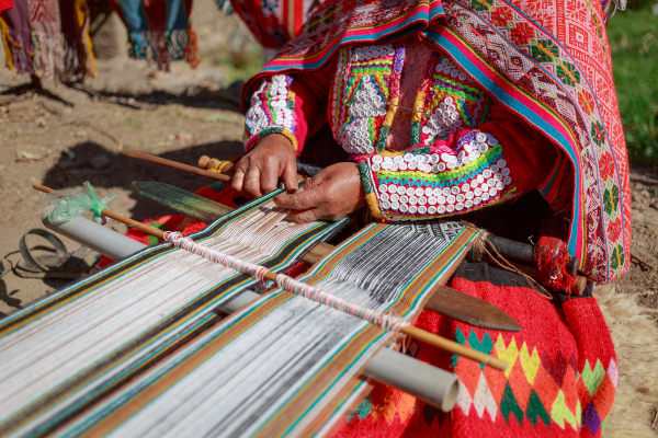Mulher com roupas coloridas realizando trabalho manual no Peru, um dos países da América Andina.