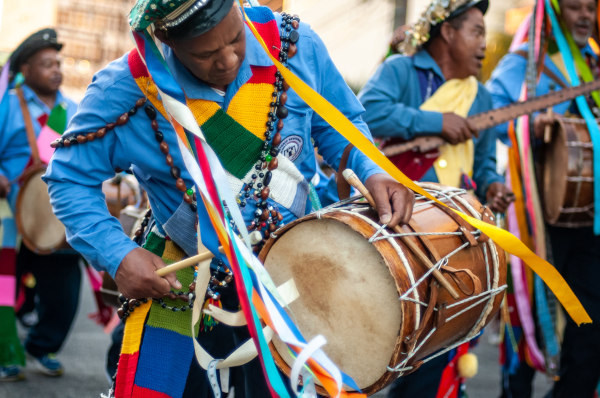 Ritmista com roupas coloridas tocando o tambor em festa do maracatu, uma expressão da cultura popular.