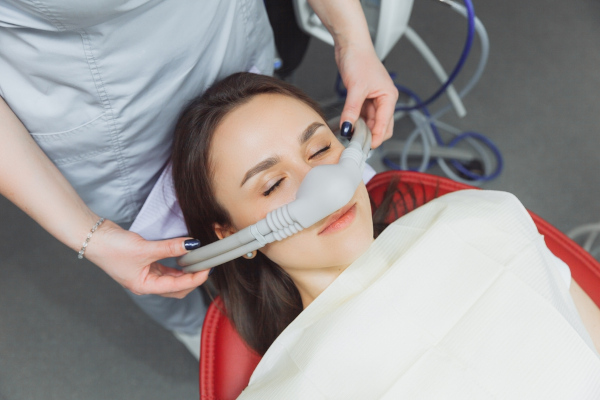 Dentista colocando máscara de sedação de óxido nitroso em paciente.