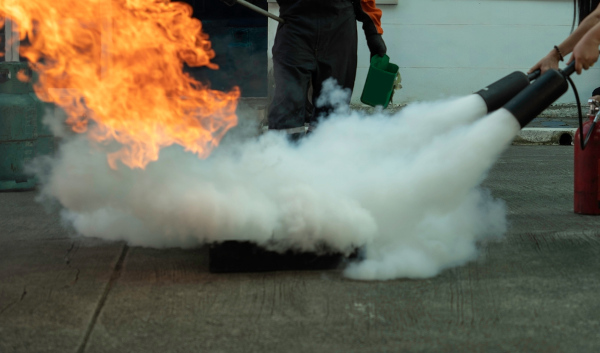 Pessoa apagando fogo com um extintor de incêndio à base de dióxido de carbono (CO₂).