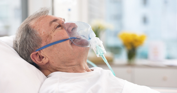 Homem idoso respirando com a ajuda de oxigênio no hospital.